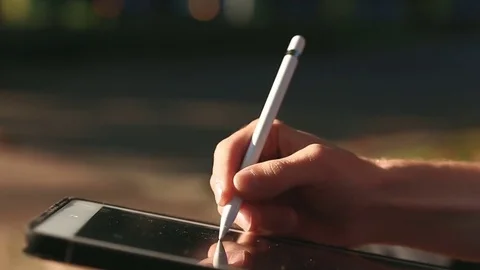 Artist drawing a sketch on tablet using stylus at park Video stock 82360545