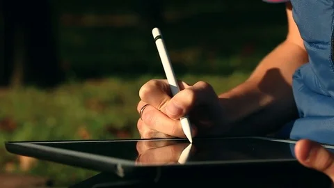 Artist drawing a sketch on tablet using stylus at park Video stock 82360771