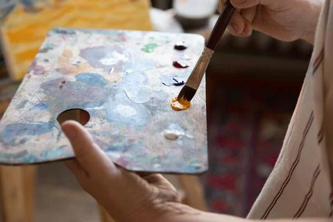 Artist holding rectangular palette, using paintbrush, blending paints Stock Photos