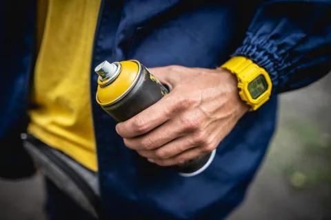 The artist holds a spray can of yellow paint in his hand Stock Photos