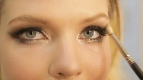 Artist-make-up applying bright basic color eye shadow to the eye of a girl Stock Footage 87684325