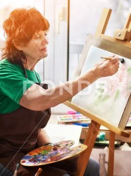 Artist painting easel in studio. Authentic senior woman. Stock Photos