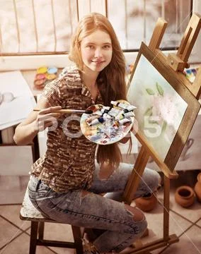 Artist painting on easel in studio. Girl paints with brush. Stock Photos