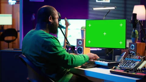 Artist plays midi controller synthesizer next to greenscreen layout Stock Footage 281455494