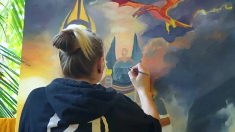 The artist, sitting with her back to the camera, creates on a large canvas. Stock Footage 268785158