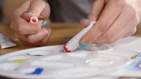 An artist squeezes out some red paint from a tube of oil paint Stock Footage