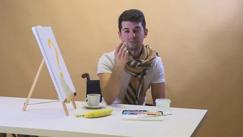 The artist at the table eats a banana and waits for inspiration Stock Footage 125540907