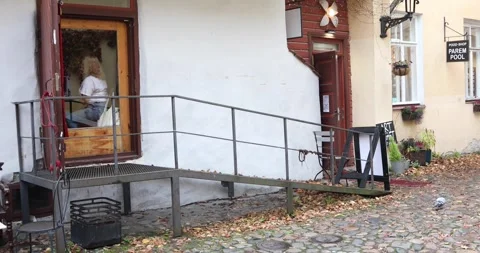 Artist at work behind window above metal ramp in cobbled Tallinn yard Stock Footage 321049080