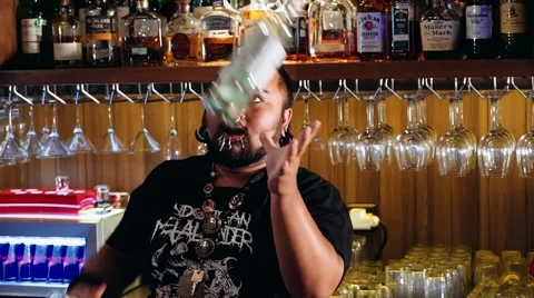 Artistic bartender with piercings + dreadlocks juggling bottle torch and shaker Stock Footage 65398831