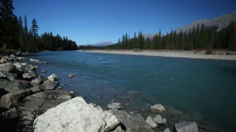 ARTISTIC BLUE GLACIAL RIVER OUT OF FOCUS WITH FOREGROUND ROCK IN FOCUS Stock Footage 59072441