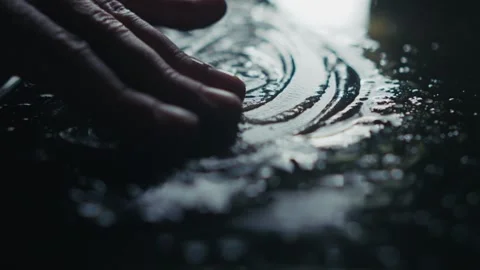 An artistic capture of fingers interacting with a fluid surface, creating Stock Footage 309474180
