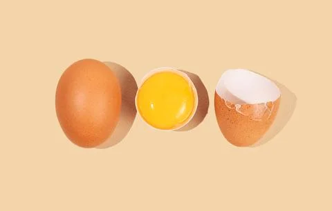 An artistic composition of brown eggs on a yellow background with one crack.. Stock Photos