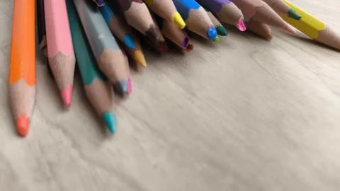 Artistic composition of sharp multicolor pencils over wooden surface. Horiz.. Stock Photos