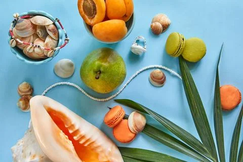 An artistic display on a blue table with seashells, macarons, and a model ship Stock Photos