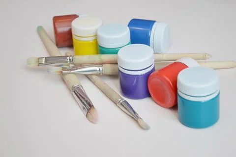 Artistic jars with multi colored gouache paints and brushes, close up. Workin Stock Photos