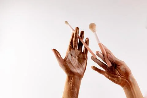 Artistic Representation of Makeup Application with Bronzer on Hands and Brushes Stock Photos