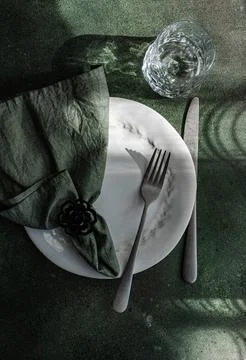 An artistic table setting featuring a white plate with a decorative napkin, u Stock Photos