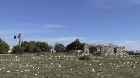 Artistic windpump windmill next to old farmhouse ruins and a stone wall Video stock 112532031