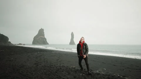 Artistic young man singing, dancing on Reynisfjara black sand beach, Iceland Stock Footage 254395245