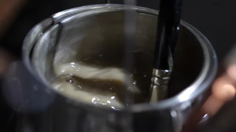 Artists cleans brush in turpentine solution in slow motion Stockbeeldmateriaal 104268745