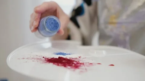 The artist's hand pours a colored patch on a palette with oil paint. Creative Video stock 147497671