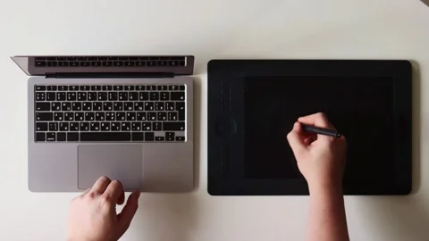 Artist's hands using a laptop and drawing tablet for digital creation Stock Footage 337173532