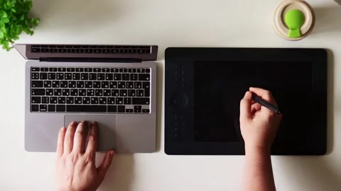 Artist's hands using a laptop and drawing tablet for digital creation Stock Footage 337173823