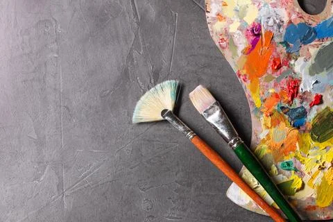 Artist's palette, brushes and paints on grey table, flat lay. Space for text Stock Photos