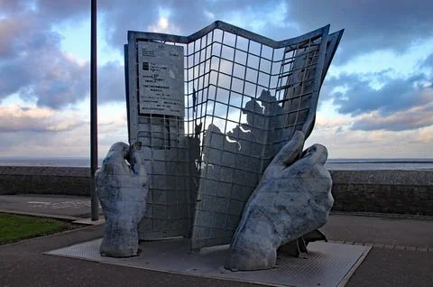 An artwork of two hands holding a gridlike newspaper on Minehead seafront Stock-Fotos