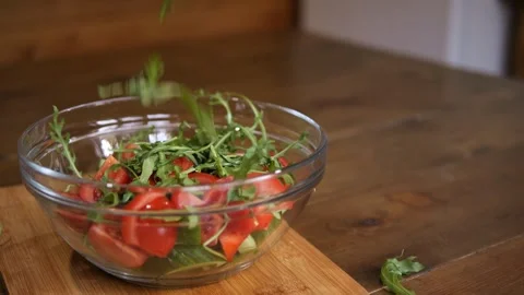 Arugula gently falls onto the prepared vegetable salad, enriching its flavor Video stock 264484789