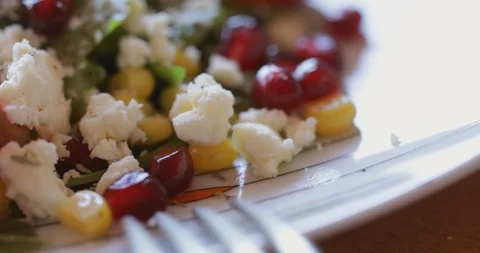 Arugula salad with cherry tomatoes, soft cheese, sweetcorn and pomegranate Stock Footage 121316700