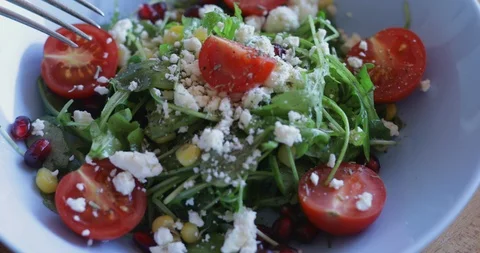 Arugula salad with soft cheese, cherry tomatoes, sweetcorn and pomegranate seed Stock Footage 121319161