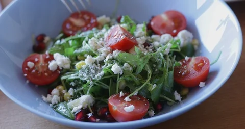 Arugula salad with soft cheese, cherry tomatoes, sweetcorn and pomegranate seed Stock Footage 122096286