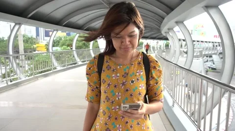 Asain Woman walking while  looking on the mobile in the city Stockbeeldmateriaal 65800031