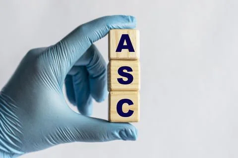ASC is an acronym on cubes held by a hand in a blue glove Stock Photos