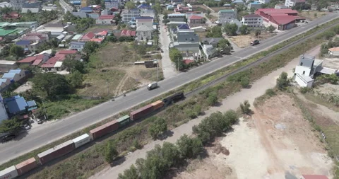 Ascending aerial: freight train moves through area alongside a parallel road. Stock Footage 334909318