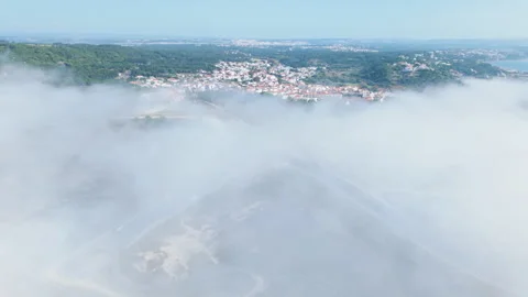 Ascending drone view over fog-covered Foz do Arelho revealing coastal village Video stock 321979044
