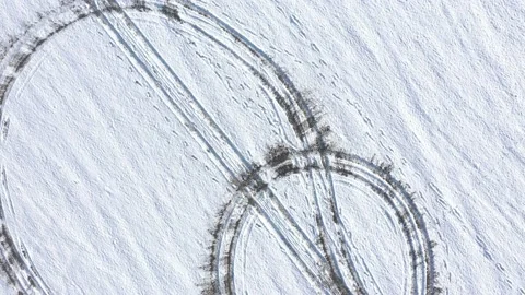 Ascending over the hill with circular vehicle tracks in the snow 4K drone Stock Footage 101019044