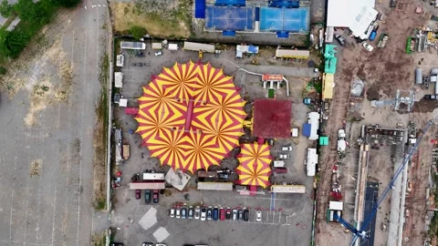 Ascending top-down drone aerial of colorful striped circus tents with carnival Stock Footage 323162134