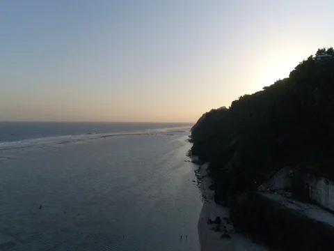 Ascent over beach, cliffs, and ocean toward sunset in Bali, Indonesia. Stock Footage 80181850