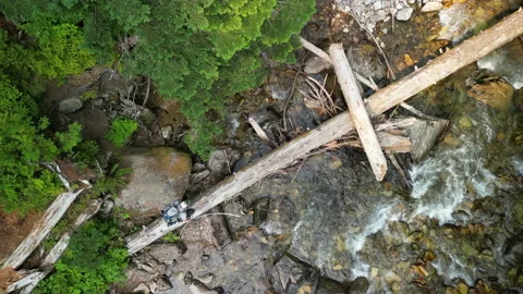Ascent of Straight-Down View of Hiker Walking Across Fallen Tree to Reveal River 库存影片 224948905