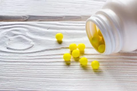 Ascorbic acid is poured out from packing on a wooden background Stock Photos