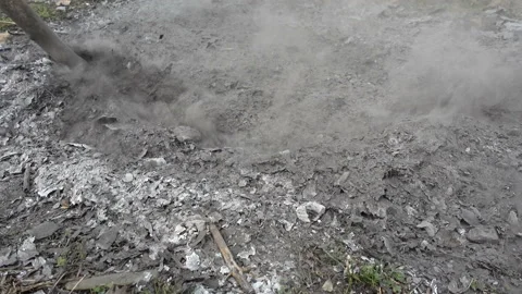 The ash of a burnt fire is touched with a stick in 4K Stock Footage 152292790