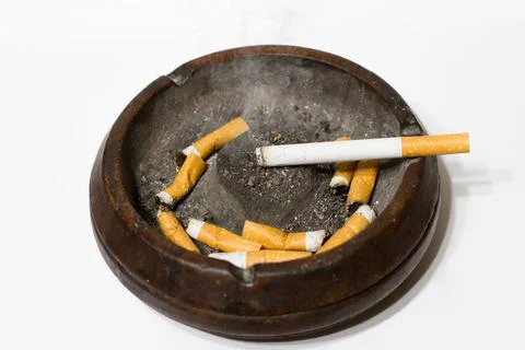 Ashtray with extinguished cigarettes and a lit cigarette on a white backgroun Stock Photos