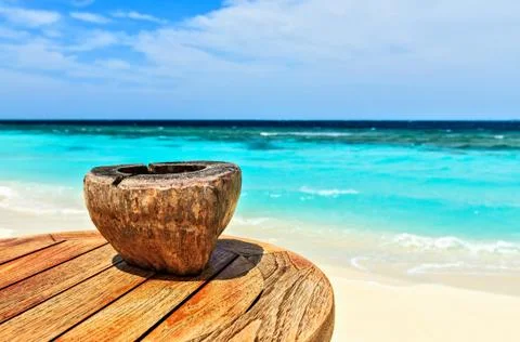 Ashtray made of coconut is on a beach table Foto stock