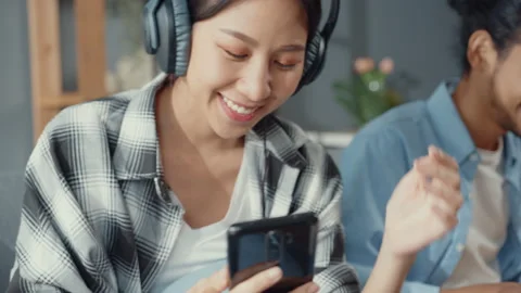 Asia couple use laptop computer work with women use smartphone listen music. Stock Footage 153021328