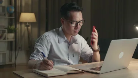 Asia Man With Laptop Computer Calling On Sartphone From Home At Night Stock Footage 154917624
