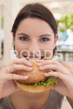 Asia, Thailand, Young Woman Eating Hamburger, Smiling, Close-Up, Portrait