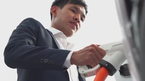 Asia young inserts the electrical connector to charge the batteries. Stock Footage 210735250