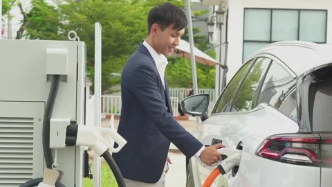 Asia young plugging wire into the car. Stock Footage 210735938